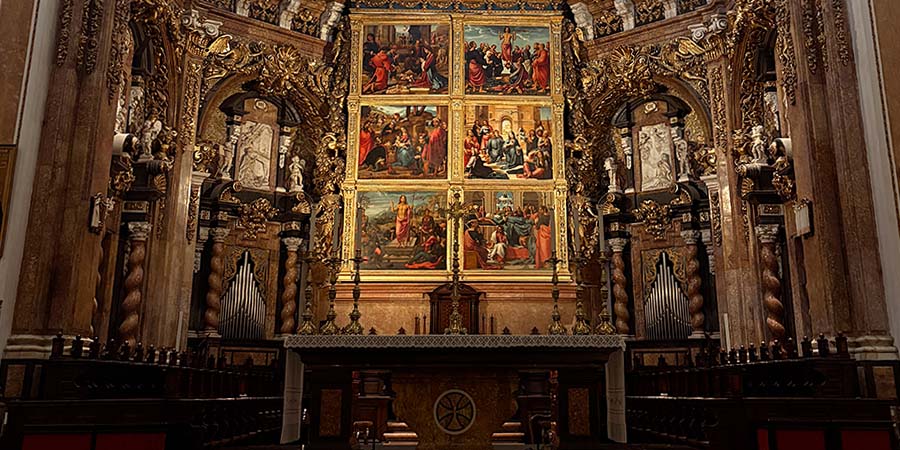 Interior of Valencia Cathedral, featuring an ornate golden altar with religious paintings, statues, intricate carvings, and organ pipes. 